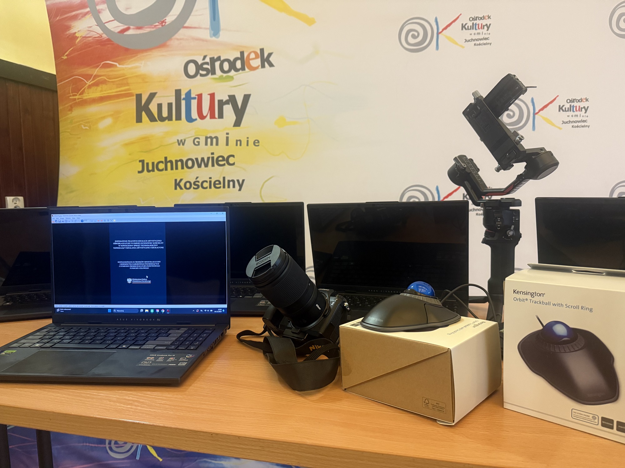 zdjęcia przedstawiają sprzęt (laptopy, aparat fotograficzny, myszy komputerowe typu trackball) zakupione w ramach projektu „Doposażenie Pracowni Edukacji Artystycznej Ośrodka Kultury w Gminie Juchnowiec Kościelny w nowoczesny sprzęt technologiczny wspierający działania artystyczne i edukacyjne